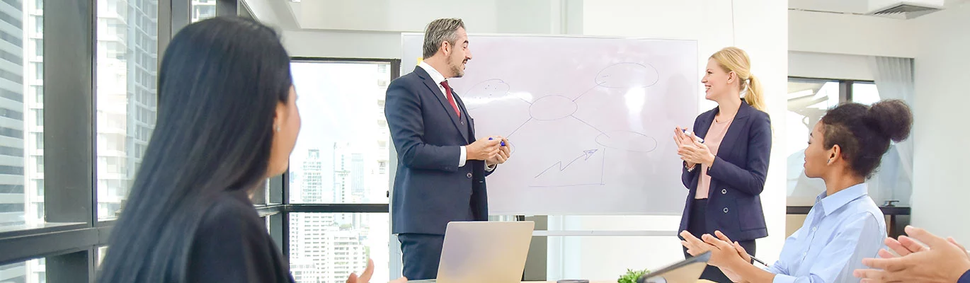 Students sit in front of a laptop, while two professionals discuss the CompTIA Pentest+ Course